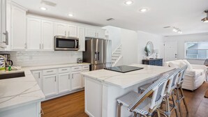 Una cocina moderna con armarios blancos, electrodomésticos de acero inoxidable y una isla de mármol.