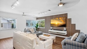 Una sala de estar moderna con un televisor grande, un sofá, un sillón a rayas y una mesa de centro.