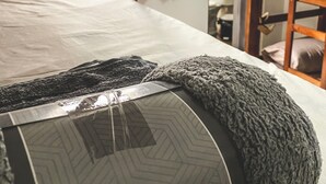 Una cama litera con colchón y almohadas, una escalera de madera y una ventana con cortinas.