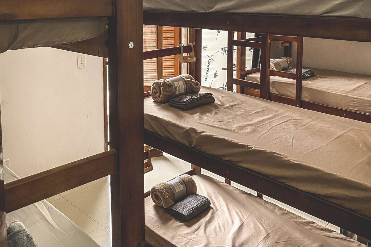 A bunk bed room with wooden frames and beige bedding.