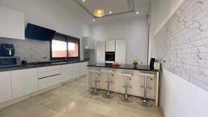 A modern kitchen with white cabinets, a black countertop, and a bar area with stools.