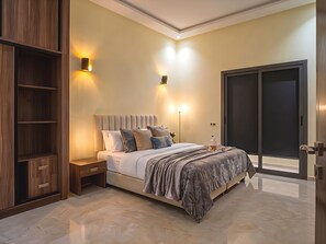 A modern bedroom with a bed, bedside tables, a wardrobe, and a sliding door. - Entire Villa in M6 I Modern Luxury Estate with Heated Pool, Gym, Hammam & Garden (Marrakesh)