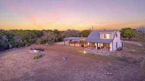 A single-story house with a covered patio, a fire pit, and a lawn.