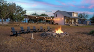 Una casa con porche cubierto, mobiliario exterior y una chimenea.