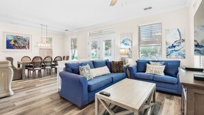 Un salon spacieux avec un canapé d’angle bleu, une table basse en bois et un ventilateur de plafond.