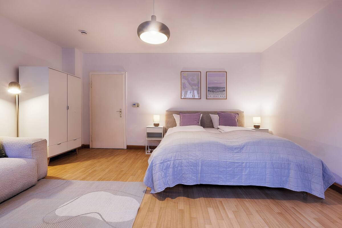 Une chambre à coucher avec un lit, des tables de chevet, une armoire et une lampe.