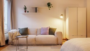 A cozy living room with a sofa, a small table, a bookshelf, and a wardrobe. - homie stay karmeliten (Würzburg)