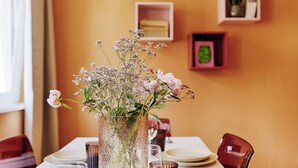 A dining table set with plates, glasses, and a vase with flowers. - homie stay karmeliten (Würzburg)