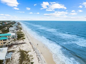 A coastal hotel with multiple buildings, a sandy beach, and the ocean.