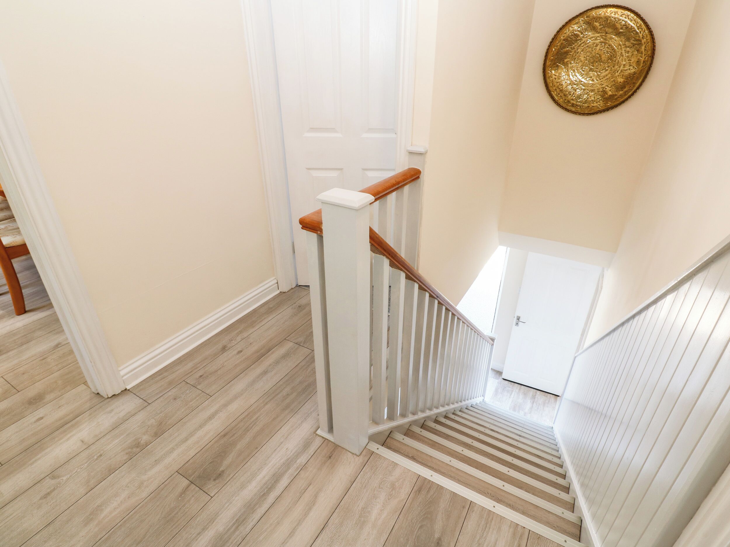 A wooden staircase with white railings and a beige floor.