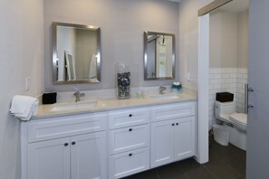 Un baño moderno con dos lavamanos, un espejo grande y un inodoro.