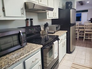 A kitchen with a microwave, stove, toaster, and refrigerator. - Steps to the Beach - Near Ocean Annie's and Apache Pier (Myrtle Beach)