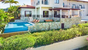A multi-story house with a swimming pool, stone walls, and outdoor seating.