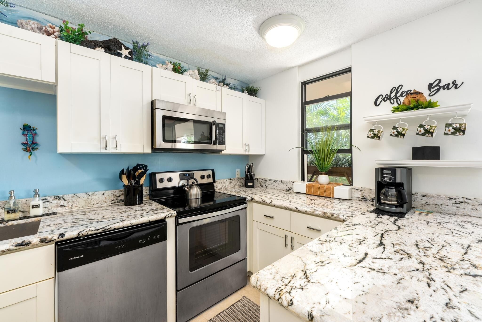 A kitchen with white cabinets, a microwave, a stove, and a coffee maker.