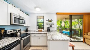 A modern kitchen with white cabinets, a built-in microwave, and a coffee bar sign.