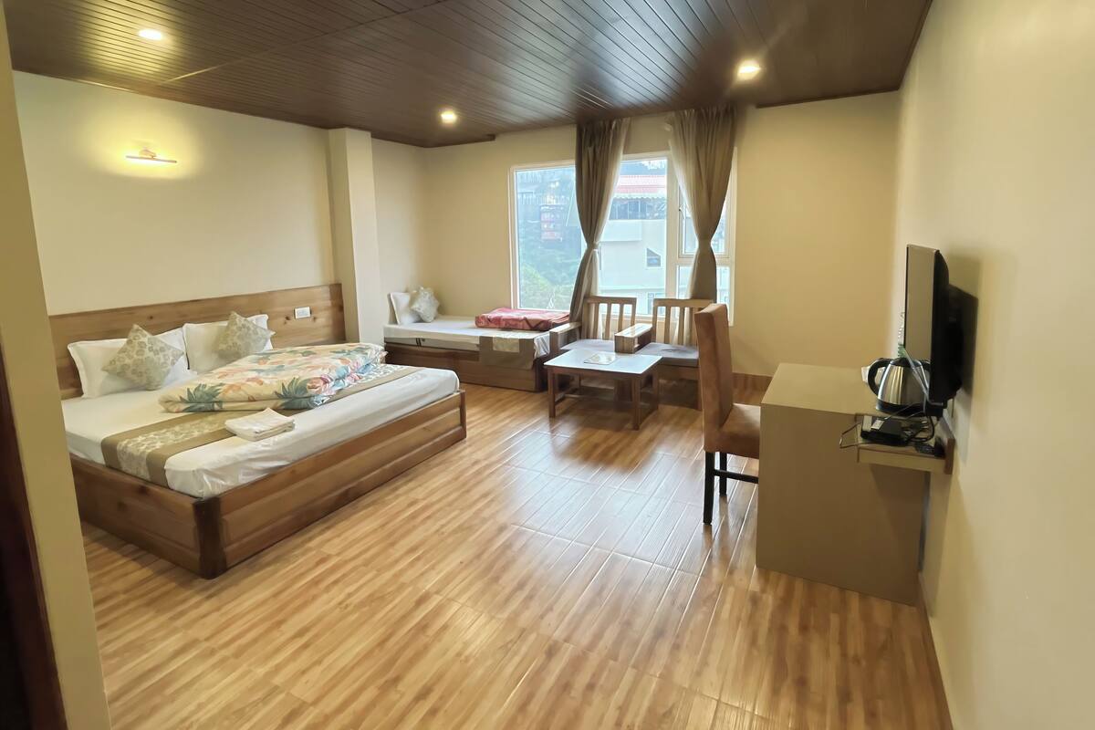 A hotel room with a wooden bed, a desk, a chair, and a television.