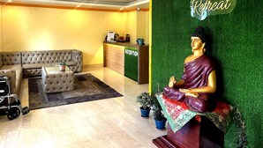 Un espace d’accueil comprenant un canapé, un comptoir de réception et une statue de Bouddha.