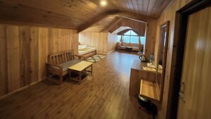 L’intérieur d’un chalet en bois chaleureux et accueillant, avec un lit en mezzanine, une table à manger et un coin cuisine.