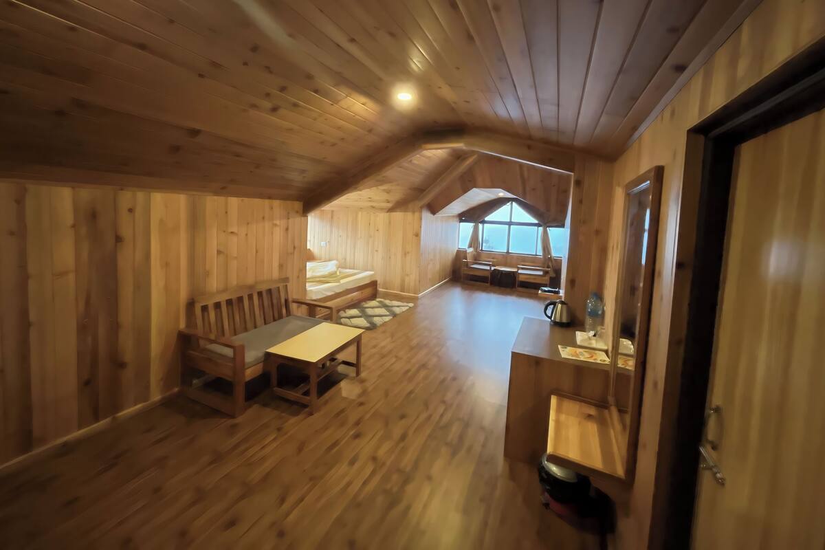 A cozy wooden cabin interior with a loft bed, a dining table, and a kitchen area.