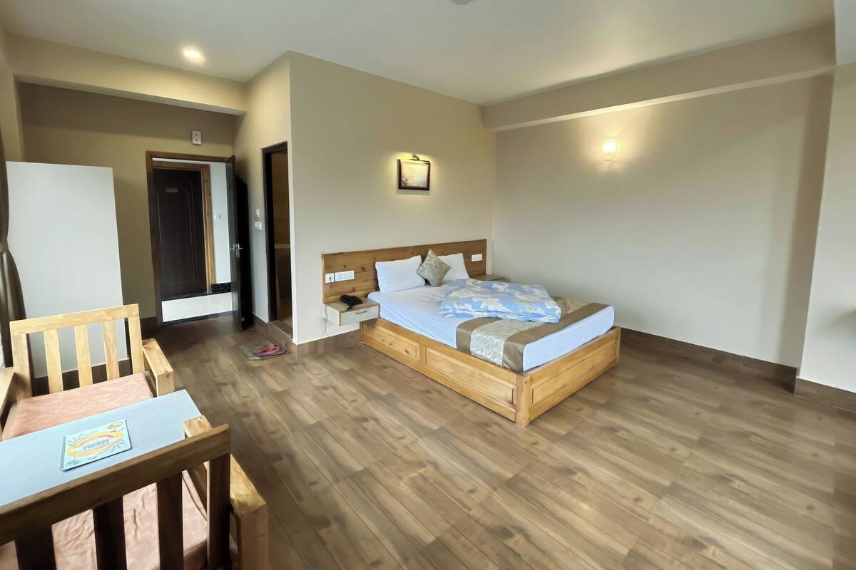 A bedroom with a wooden bed, bedside table, and a desk with a chair.