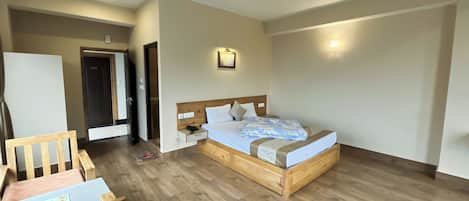 A bedroom with a wooden bed, bedside table, and a desk with a chair.