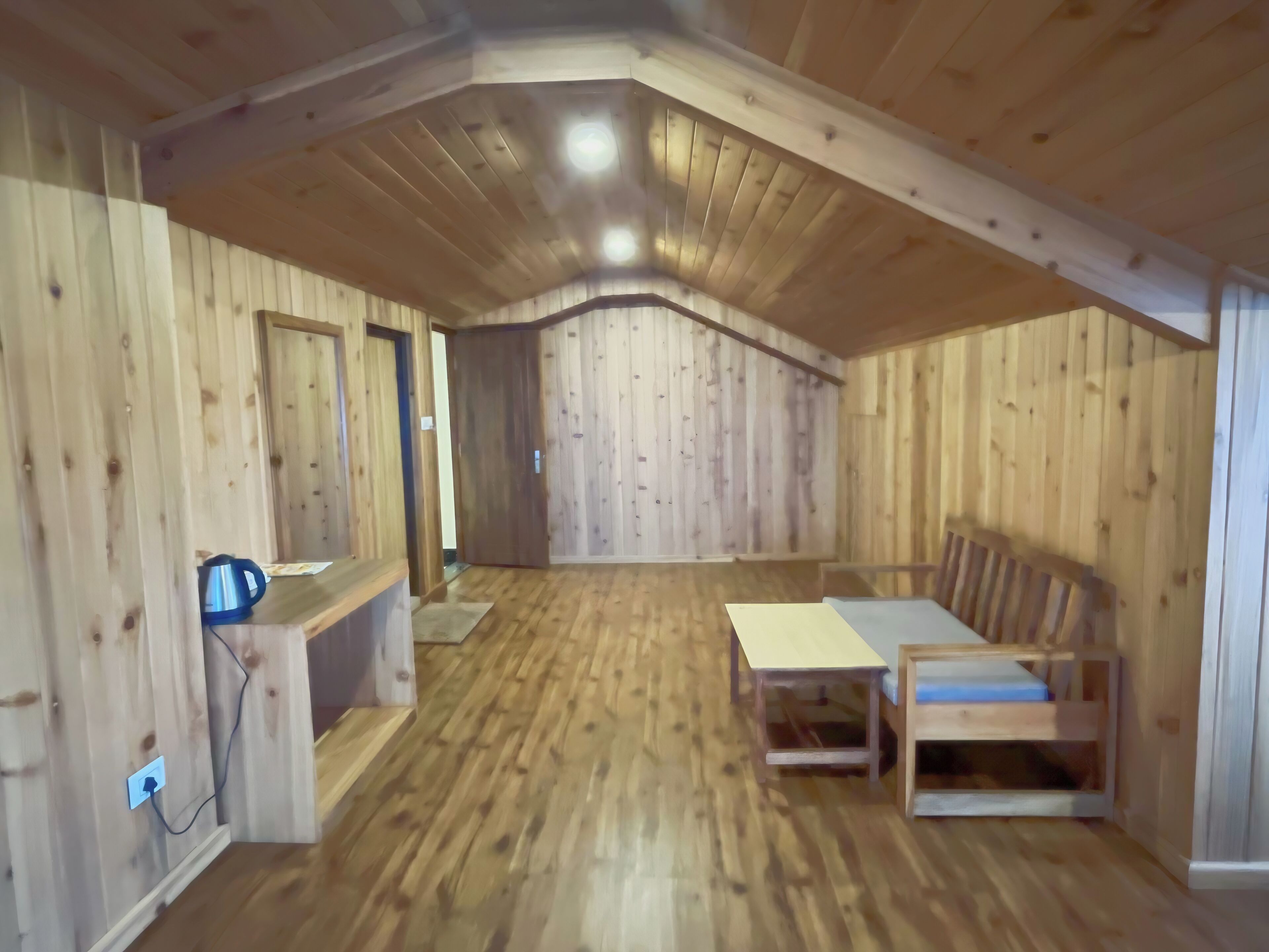A wooden interior with a high ceiling, a sofa, a small table, and a power outlet.