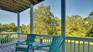 Een overdekt terras met twee turquoise Adirondack-stoelen en een tafeltje met een plant.