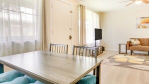 Een eetgedeelte met een tafel, stoelen, een bank en een plafondventilator.