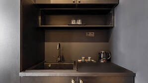 A compact kitchen with a sink, a kettle, and a shelf with glasses. - Astoria Boutique Suites - by BQA (Budapest)