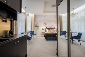 Een moderne hotelkamer met een bed, een bureau met koffiezetapparaat en uitzicht op een stadsgezicht door grote ramen.