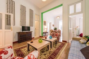 A living room with a TV, wooden coffee table, patterned rugs, and a sofa.