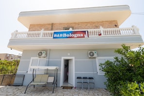 Un edificio con balcón, un cartel que dice 'B&B Bologna' y una puerta que da a un interior.