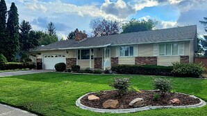 A single-story house with a garage, a front porch, and a well-maintained lawn with a circular flower bed. - Beautifully Updated Home on Oak Trail Drive in IF
 (Idaho Falls)