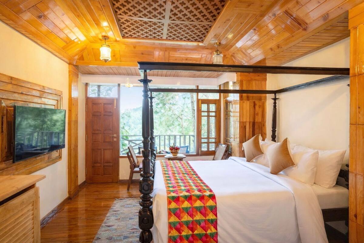 A wooden-paneled bedroom with a bed, a television, and a balcony.