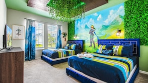 A bedroom with two beds, a TV, and a mural of a character.