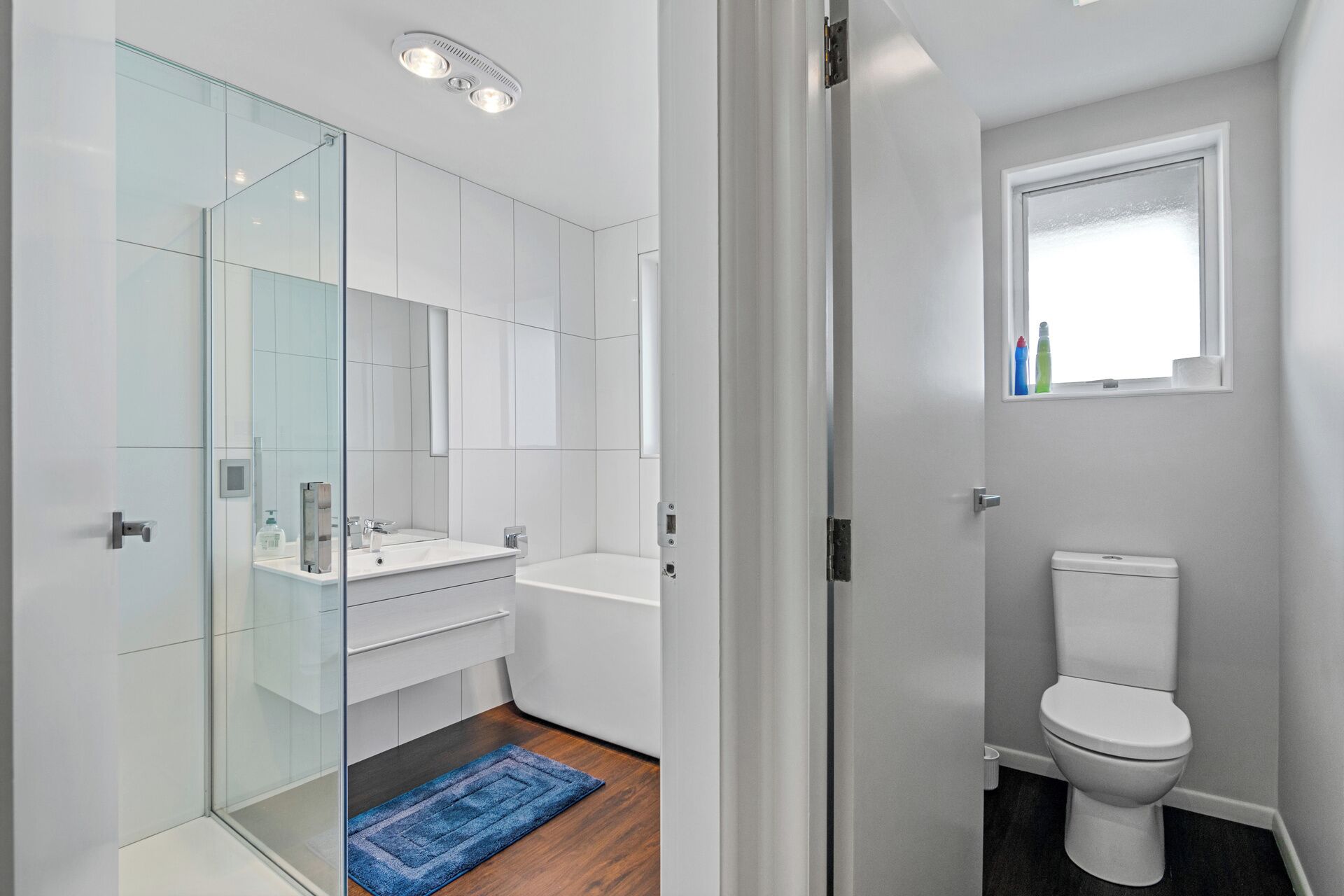 A modern bathroom with a glass shower enclosure, a white sink, and a toilet.