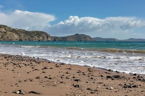 Une plage au paysage rocheux et aux vagues calmes.