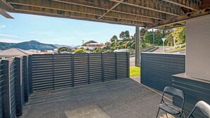 A covered outdoor area with a view of a road and hills.