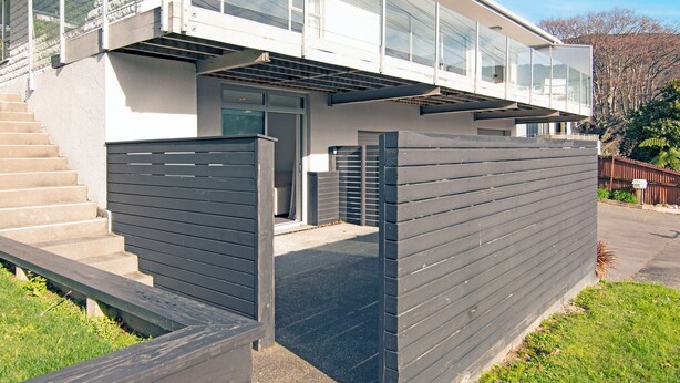 A modern two-story house with a covered outdoor area, a garage, and a fenced yard.