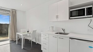 A modern kitchen with white cabinetry, a built-in microwave, and a stainless steel sink.