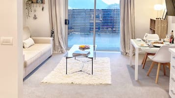 A modern living room with a sofa, a coffee table, and a dining area with a table and chairs.