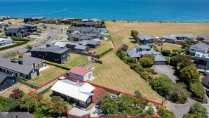 An aerial view of a residential area with houses, a large open field, and a body of water in the background. - Lakeside Haven - Taupo Holiday Home (Wharewaka)