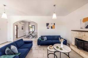 Un salón moderno con dos sofás, una chimenea y un comedor al fondo.