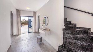 A modern interior with a staircase, a glass door leading outside, and a white console table with a mirror.