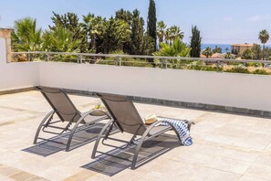 Una terrazza sul tetto con due sdraio, un cappello e un asciugamano a righe.