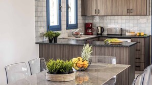 A modern kitchen with a marble countertop, wooden cabinets, and a dining area with a glass table and chairs.