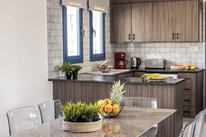 Una cucina moderna con un piano di lavoro in marmo, mobili in legno e un'area pranzo con tavolo e sedie in vetro.