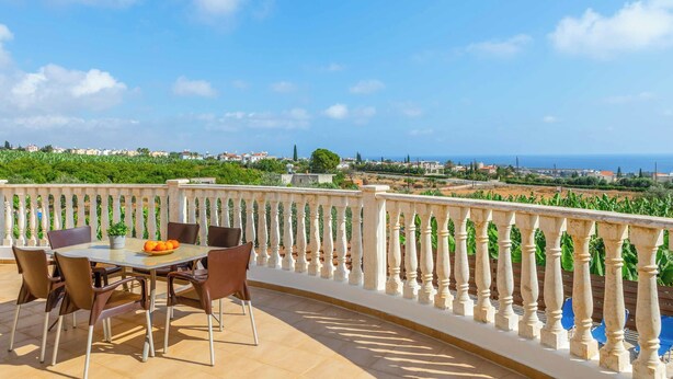 Una terraza con mesa y sillas, vista al mar y una barandilla.