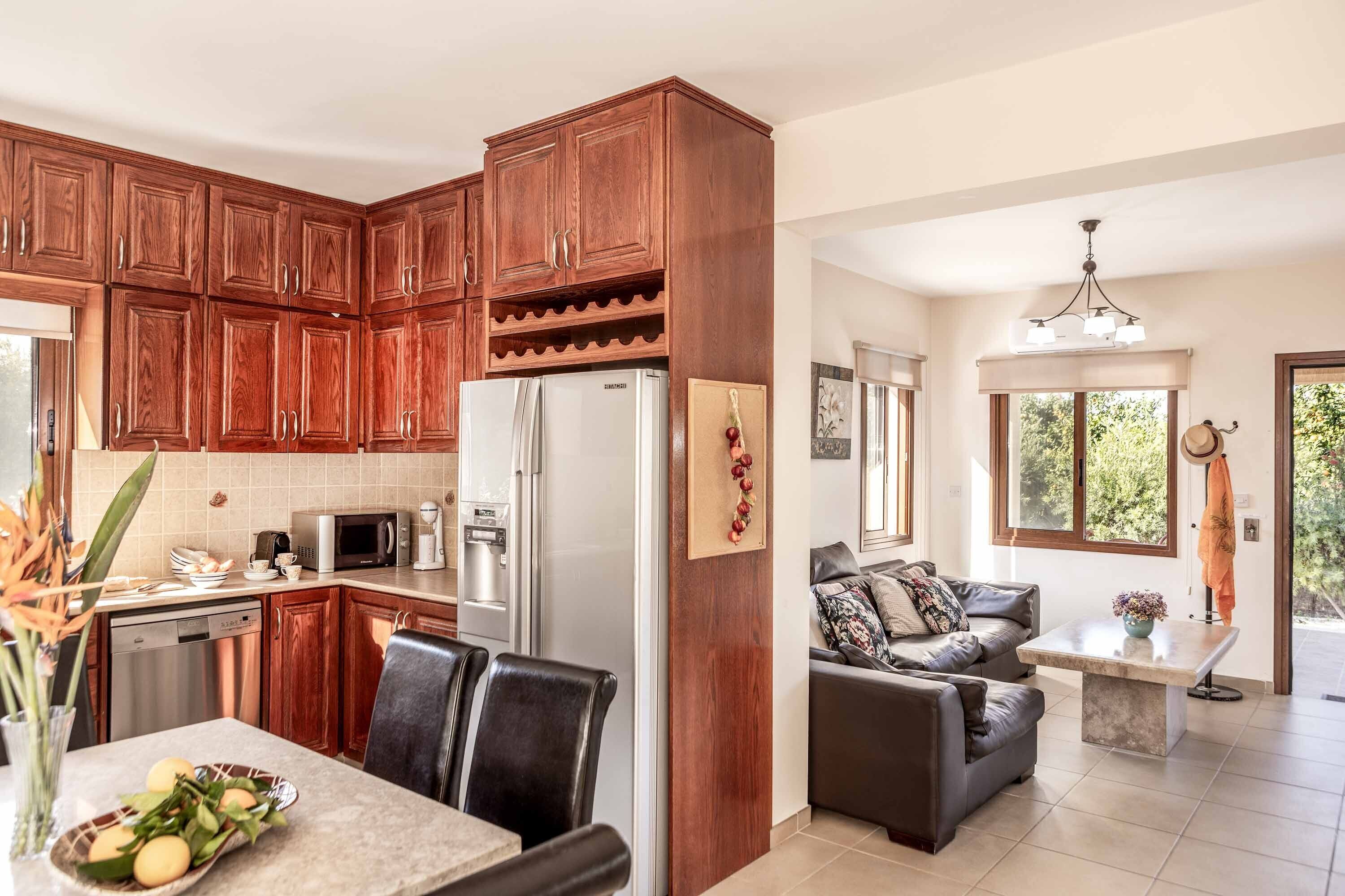 A modern kitchen with wooden cabinets, stainless steel appliances, and a dining area with a table and chairs.