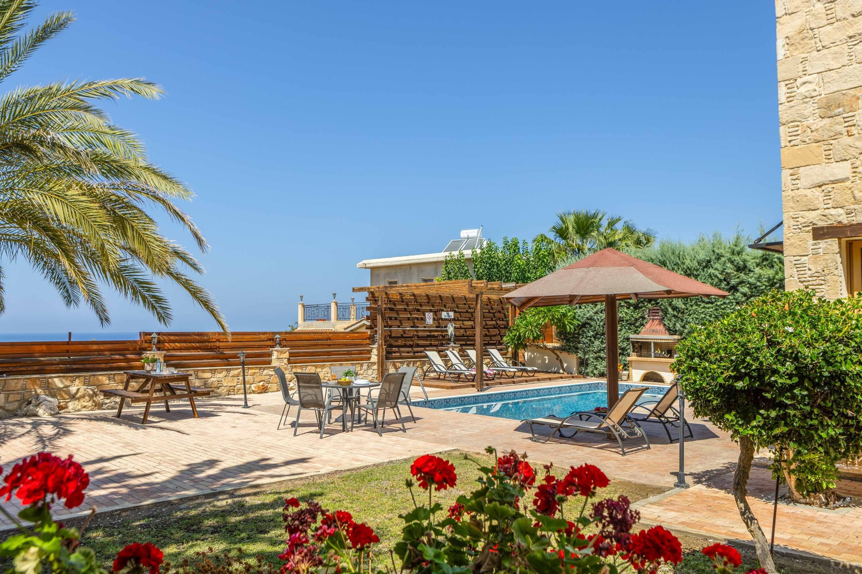 A poolside area with lounge chairs, a table, and a pergola.